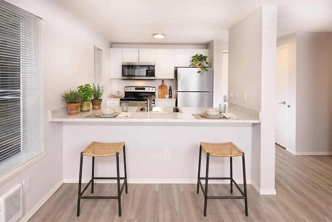 Kitchen with stainless steel appliances, white cabinets, light countertops, and a breakfast bar w...