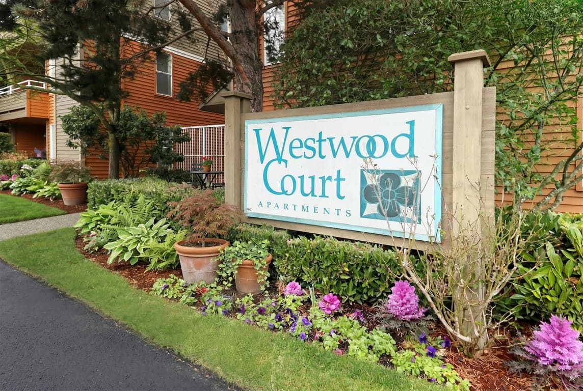 Westwood Court apartment living room in Seattle, WA with large windows, wood floors, and seating.